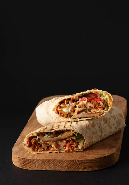 Shawarma, rotolo in lavash, carne alla griglia, con verdure, sandwich, tagliato su uno sfondo nero, verticale, copia spase — Foto Stock