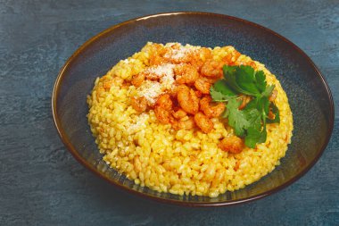 Karidesli risotto, bir kasede, dokulu bir yüzeyde, yanında taze kişniş tabağı, ev yapımı, insan yok.,