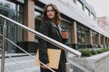 Sakin, güzel bayan, aşağıya inip kahve içerken hafif bir gülümsemeyle uzaklara bakıyor.