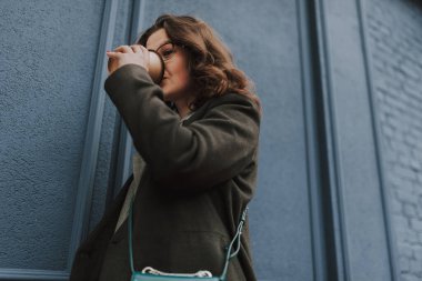 Genç bayan kahve aşığı en sevdiği içeceği içiyor ve mavi duvardaki kağıt bardaktan içiyor.