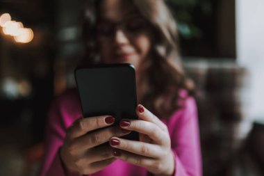 İçeriye mesaj yazarken akıllı telefon kullanan mutlu genç bayanı kapat