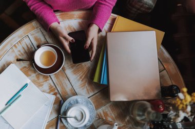 Kahve evinde masada otururken cep telefonu tutan kadınların üst görüntüsü.