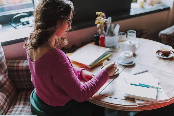 Genç ve çekici bir kadın kafeteryada otururken çay kaşığıyla çay izleyip karıştırıyor.