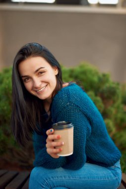 Uzun siyah saçlı çekici bir kadın sakin bir meydanda boş vaktini geçirip yalnızlığının tadını çıkarıyor.