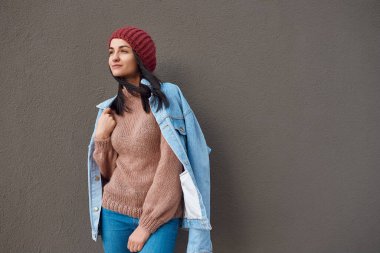 Sakin ve huzurlu genç bayan, modern bir binanın geniş bir kömür panelinin karşısında rahatça duruyor.