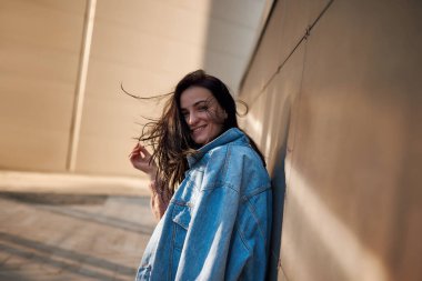 Omuzlarının üzerinden dışarı doğru eğilen kot ceketli güzel bir bayan.