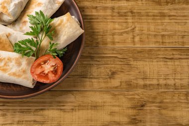 Peynirli, sebzeli ve kırsal bir tabakta yeşillikli sıcak pita ekmeği. Domates, biber, marul ve maydanozla servis edilir. Öğle yemeği için mükemmel, iş yemeği için mi yoksa yemek için mi?.