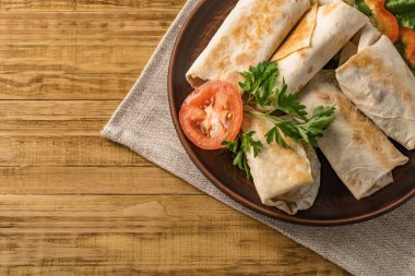 Peynirli, sebzeli ve kırsal bir tabakta yeşillikli sıcak pita ekmeği. Domates, biber, marul ve maydanozla servis edilir. Öğle yemeği için mükemmel, iş yemeği için mi yoksa yemek için mi?.