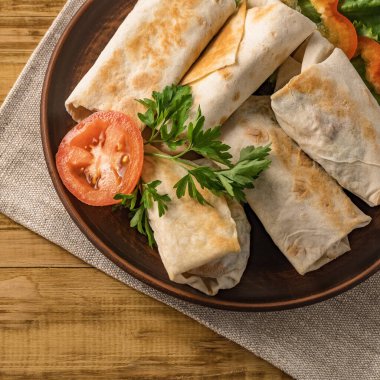 Peynirli, sebzeli ve kırsal bir tabakta yeşillikli sıcak pita ekmeği. Domates, biber, marul ve maydanozla servis edilir. Öğle yemeği için mükemmel, iş yemeği için mi yoksa yemek için mi?.