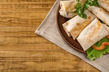 Peynirli, sebzeli ve kırsal bir tabakta yeşillikli sıcak pita ekmeği. Domates, biber, marul ve maydanozla servis edilir. Öğle yemeği için mükemmel, iş yemeği için mi yoksa yemek için mi?.