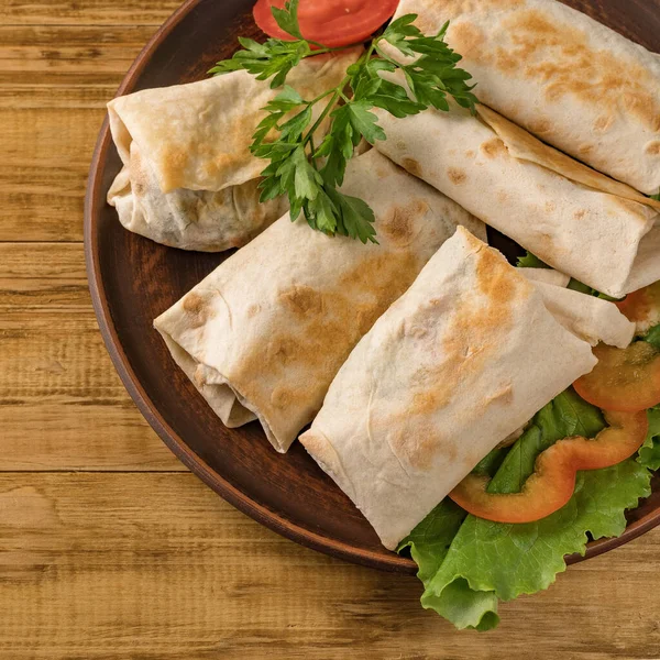 Peynirli, sebzeli ve kırsal bir tabakta yeşillikli sıcak pita ekmeği. Domates, biber, marul ve maydanozla servis edilir. Öğle yemeği için mükemmel, iş yemeği için mi yoksa yemek için mi?.