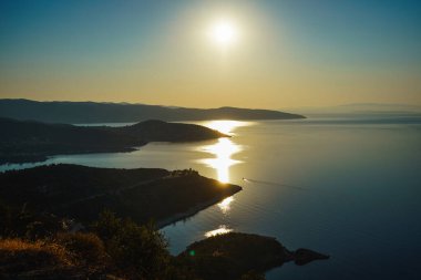 Dağdan, Akdeniz 'in güzel koylarına bakın. Batan güneşin yansıması - ay yolu. Yunanistan, Halkidiki, Pyrgadikia.