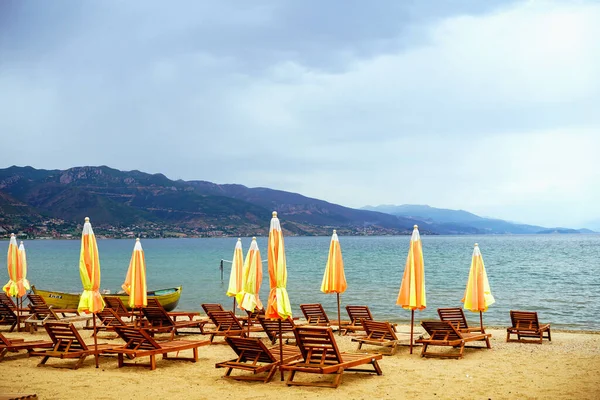 O lago mais profundo e mais antigo da Península Balcânica. Uma praia com espreguiçadeiras e guarda-sóis para relaxamento e relaxamento nas margens do Lago Ohrid . Imagens Royalty-Free