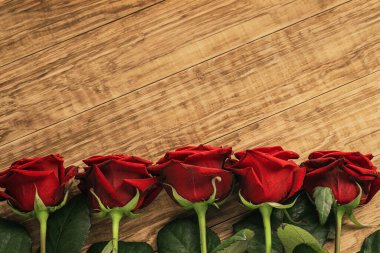 Ahşap arka planda beş kırmızı gül.