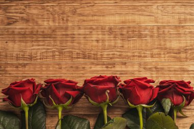 Ahşap arka planda beş kırmızı gül.
