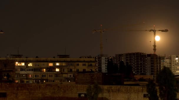 月亮的运动背景是一个大型的建筑工地 有几个起重机和住宅建筑在前景中 夜间延时射击 — 图库视频影像