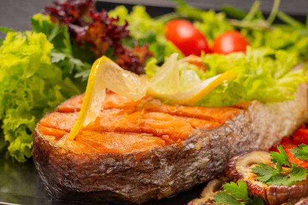 Restoranda yemek servisi yap. Yiyecek posteri - büyük porsiyon kırmızı balık, alabalık, ızgara sebzeli somon bifteği, salata, brokoli ve domates, limon ve biberiyeyle süslenmiş. Izgara sebze: patlıcan, kabak, Bulgar kırmızı biberi. Servis devam ediyor 