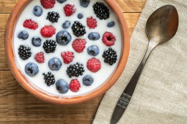 Yaban mersinli yoğurt, ahududu, böğürtlen, kil kasede keten tohumu. Vejetaryen yemeği. Sağlıklı kahvaltı, sağlıklı yemek. Restoranların, kafelerin menüsü için arka plan.
