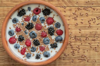 Yaban mersinli yoğurt, ahududu, böğürtlen, kil kasede keten tohumu. Vejetaryen yemeği. Sağlıklı kahvaltı, sağlıklı yemek. Restoranların, kafelerin menüsü için arka plan.