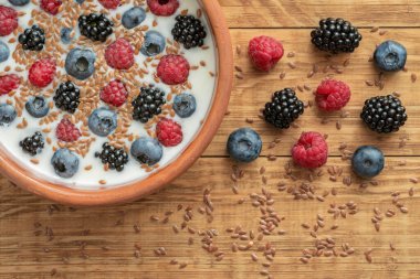 Yaban mersinli yoğurt, ahududu, böğürtlen, kil kasede keten tohumu. Vejetaryen yemeği. Sağlıklı kahvaltı, sağlıklı yemek. Restoranların, kafelerin menüsü için arka plan.