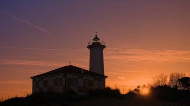 The lighthouse at sunset on the beach at the mouth of the river Tagliamento, Bibione, Venezia, Italy. clipart