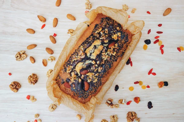 Traditional homemade marble pound cake with almond and walnuts, raisins and dry fruits around on the wooden table. Flat lay. Close up. Gluten free food concept.