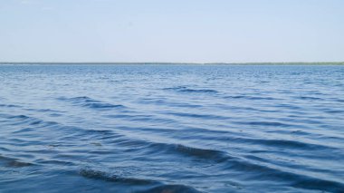 Göldeki ışık dalgaları güneşin akşam ışınlarıyla aydınlatılır. Lanet olası göl. Rusya 'da tuz gölü üzerinde rüzgarlı. Bulutsuz mavi gökyüzü. Sıcak yaz akşamı.