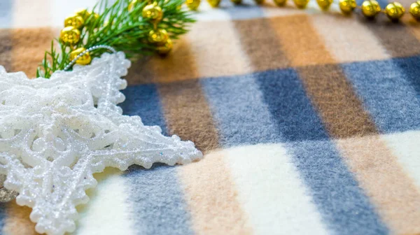 Nuovo anno e biglietto di Natale. Decorazioni natalizie su una coperta. Un ramo di abete rosso, una stella bianca e perline si trovano su una coperta a quadri invernale. Posto per il testo. Ricevuto. Focus selettivo. — Foto Stock