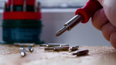 Bir çift küçük tornavida. Arka planda küçük bir tornavidanın başlığı. Cihazları tamir etmek için bir takım aletler. Tornavida kontrplağın üzerinde duruyor..