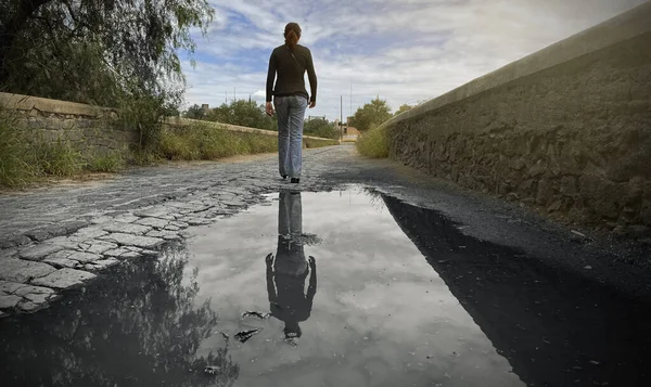 girl walking to the end of the bridge, reflection of her past in the water. Go to the future