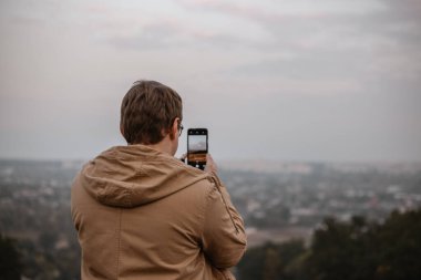 Telefonuyla manzara fotoğrafı çeken bir adam.