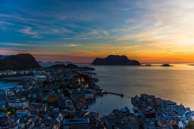 Sahildeki küçük bir köy, deniz kenarındaki evler, adadaki görkemli günbatımı gökyüzü