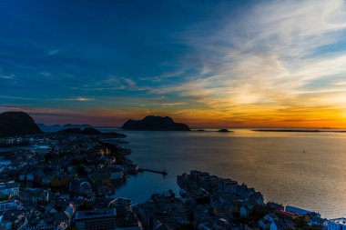 Sahildeki küçük bir köy, deniz kenarındaki evler, adadaki görkemli günbatımı gökyüzü