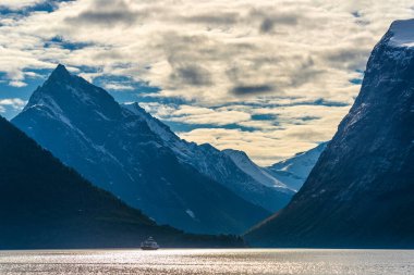 Sudaki kayık, görkemli günbatımı gökyüzü ve dağlı göl. 