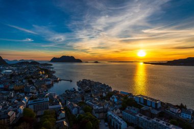 Sahildeki küçük bir köy, deniz kenarındaki evler, adadaki görkemli günbatımı gökyüzü