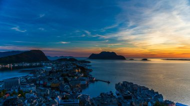 Sahildeki küçük bir köy, deniz kenarındaki evler, adadaki görkemli günbatımı gökyüzü