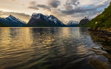 Güzel günbatımı gökyüzü, sakin göl suyu ve dağlar 