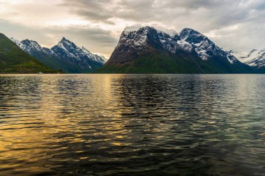 Bulutlu, göllü ve dağlı güzel gün batımı gökyüzü 