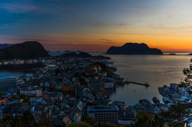 Sahildeki küçük bir köy, deniz kenarındaki evler, adadaki görkemli günbatımı gökyüzü