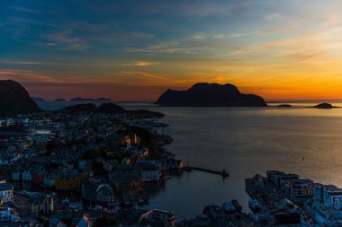 Sahildeki küçük bir köy, deniz kenarındaki evler, adadaki görkemli günbatımı gökyüzü