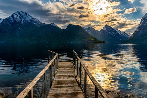 木制码头 雄伟落日的天空映照在湖水和山中 — 图库照片