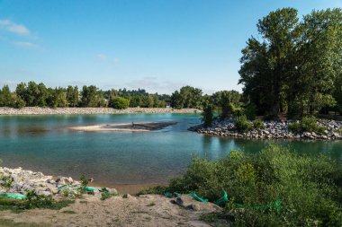 Sakin bir nehir ve yemyeşil bitki örtüsüyle güzel doğal bir manzara.