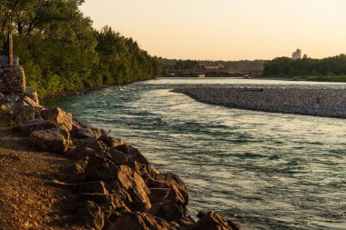 Sakin bir nehir ve yemyeşil bitki örtüsüyle güzel doğal bir manzara.