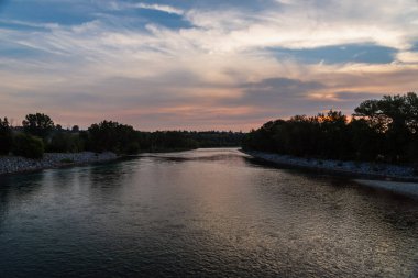 Sakin bir nehir ve yemyeşil bitki örtüsüyle güzel doğal bir manzara.