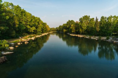 Sakin bir nehir ve yemyeşil bitki örtüsüyle güzel doğal bir manzara.