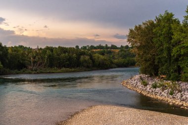 Sakin bir nehir ve yemyeşil bitki örtüsüyle güzel doğal bir manzara.