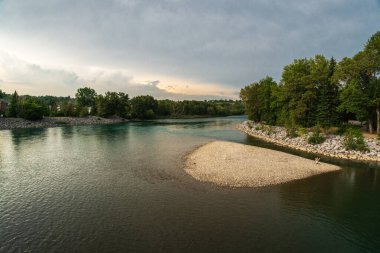 Sakin bir nehir ve yemyeşil bitki örtüsüyle güzel doğal bir manzara.