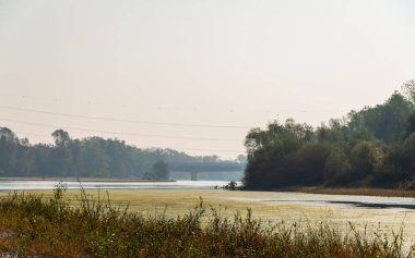 İtalya, Lombardy 'deki sakin nehir ve güzel kırsal alan üzerindeki köprü