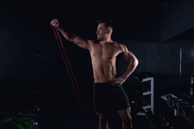 Lastik bantlı egzersizler spor salonunu, seksi bir vücut geliştiriciyi, spor yaşam tarzını, ev sporlarını gösteriyor.