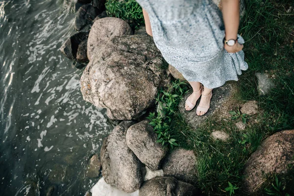 Deniz kıyısında büyük taşların yanında bir kız duruyor. Yukarıdan görüntüle